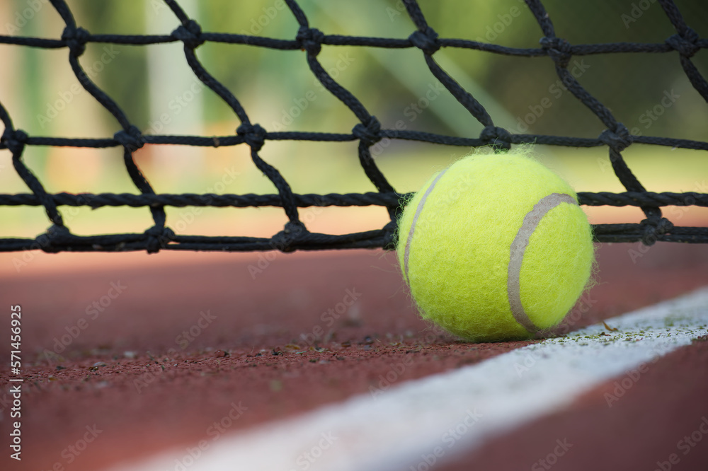 Tennis ball in the black net on hard tennis court surface
