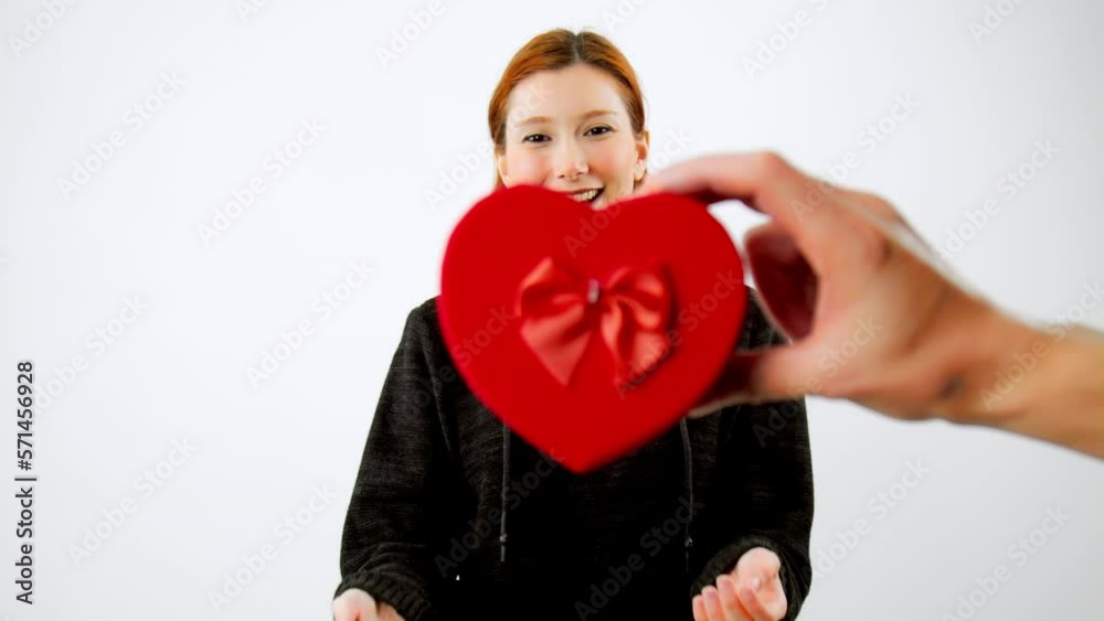The moments in slow motion that show the joy of the young woman as she receives a heart-shaped gift box from a man The moments in slow motion that show the joy of the young woman as she receives a heart-shaped gift box from a man