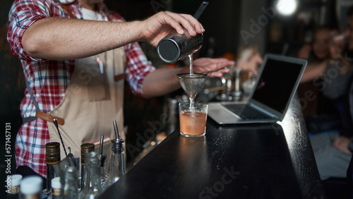male bartender pouring a cocktail from a shaker. best service.