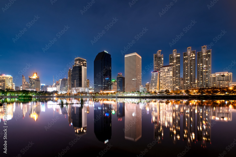 Night, modern highrises reflecting in lake by park. Bangkok, Thailand