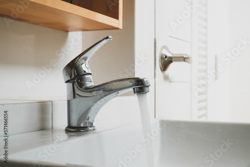 Running water tap  Interior of bathroom with sink basin faucet  Open chrome faucet washbasin  Modern design of bathroom.