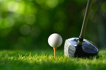 Close-up golf ball on tee with golf drivers at golf course.