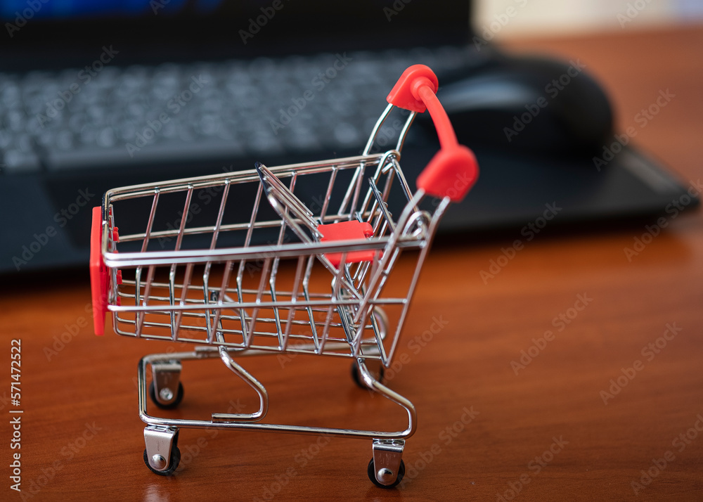 Online shopping. Supermarket cart on open laptop. E-commerce, buying goods or services over the Internet, buying goods in online stores using the concept of digital technology. Online shopping. Supermarket cart on open laptop. E-commerce, buying goods or services over the Internet, buying goods in online stores using the concept of digital technology.