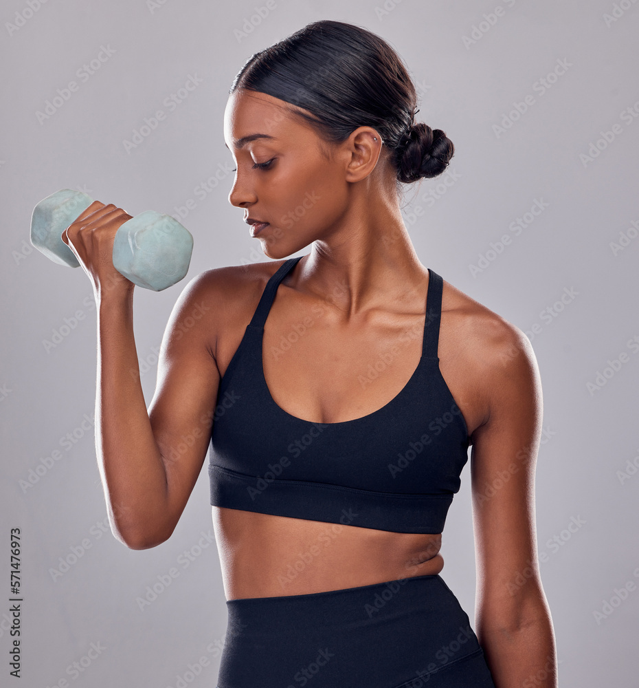 Black woman, dumbbells exercise and studio for muscle development, wellness and self care with focus. Gen z bodybuilder girl, training and strong healthy body with gym equipment by gray background Black woman, dumbbells exercise and studio for muscle development, wellness and self care with focus. Gen z bodybuilder girl, training and strong healthy body with gym equipment by gray background