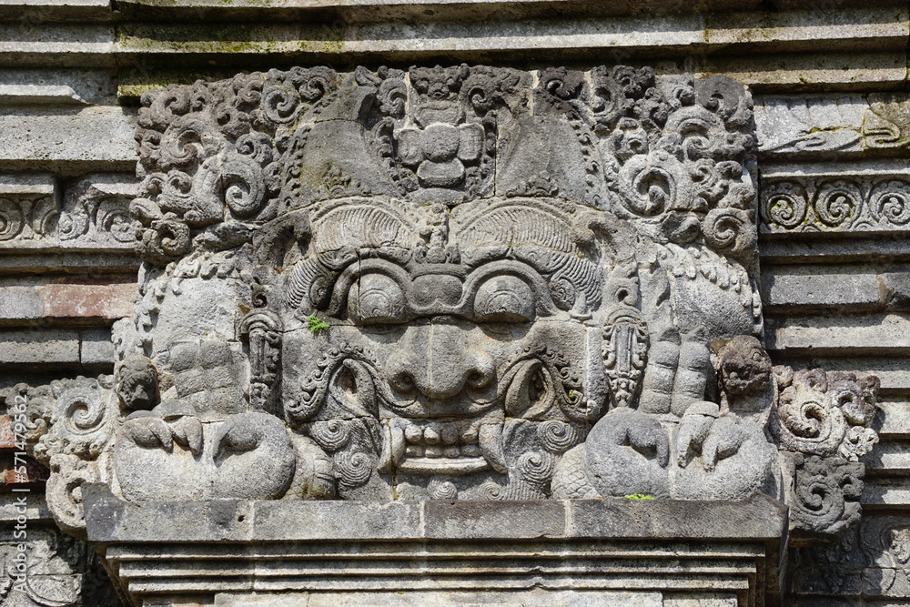The relief of kala kirtimukha on penataran temple. Kala kīrttimukha is the name of a swallowing fierce monster face with huge fangs and a gaping mouth The relief of kala kirtimukha on penataran temple. Kala kīrttimukha is the name of a swallowing fierce monster face with huge fangs and a gaping mouth