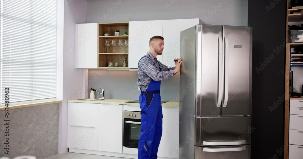 Male Worker Repairing Refrigerator With Screwdriver Male Worker Repairing Refrigerator With Screwdriver