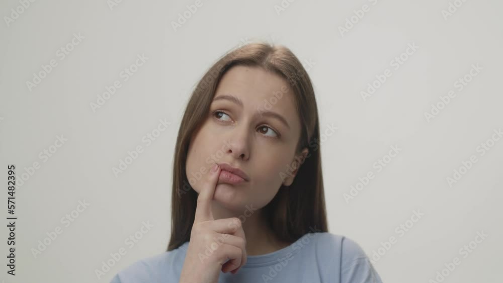 Pensive girl touching her lips and showing the idea sign. Close up view of brunette woman looking up while thinking about something on white background Pensive girl touching her lips and showing the idea sign. Close up view of brunette woman looking up while thinking about something on white background