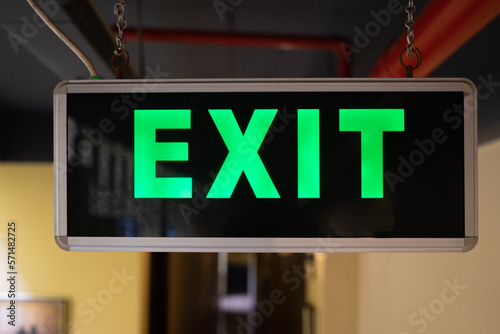 A light box with the green inscription EXIT hangs in a hostel corridor. Exit sign