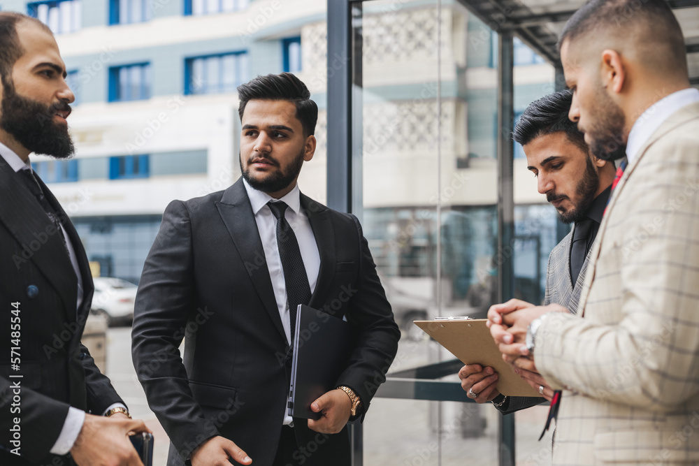 Business people outdoor meeting. Men in jackets discuss working moments together by brainstorming. Teamwork and partnership in business processes Business people outdoor meeting. Men in jackets discuss working moments together by brainstorming. Teamwork and partnership in business processes