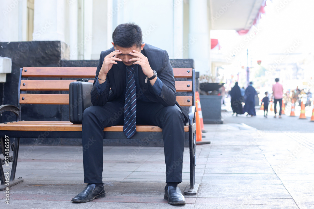 Young businessman sitting on chair, thinking about company, feeling sad and upset, getting bad news from office. Young businessman sitting on chair, thinking about company, feeling sad and upset, getting bad news from office.