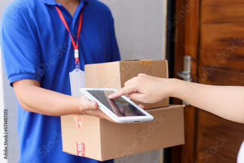 Cropped shot of customer sign on tablet while receiving package from deliveryman photo