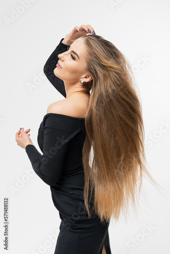 Portrait of a young woman in a black dress with long well-groomed hair. Hairstyle for photography
