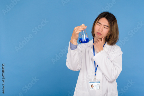 young scientist with a pensive expression with a test tube with blue liquid in his hand
