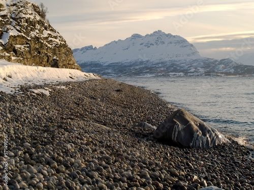 Pebble beach and snowy landscape in Northern Norway