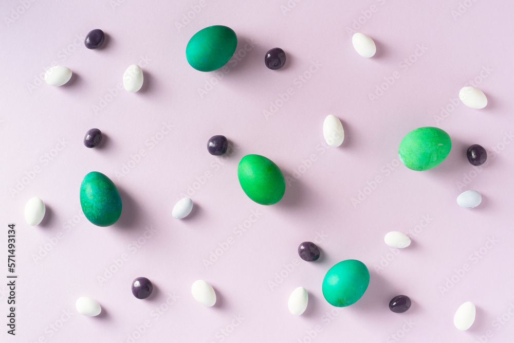 Green easter eggs with colorful candies on purple background.