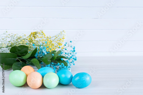 Happy Easter. Congratulatory easter background. Easter eggs and flowerson white table.