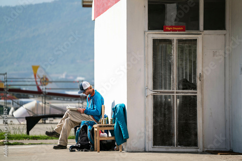 Man sits outside of flight dispatch office writing in Bhutan photo