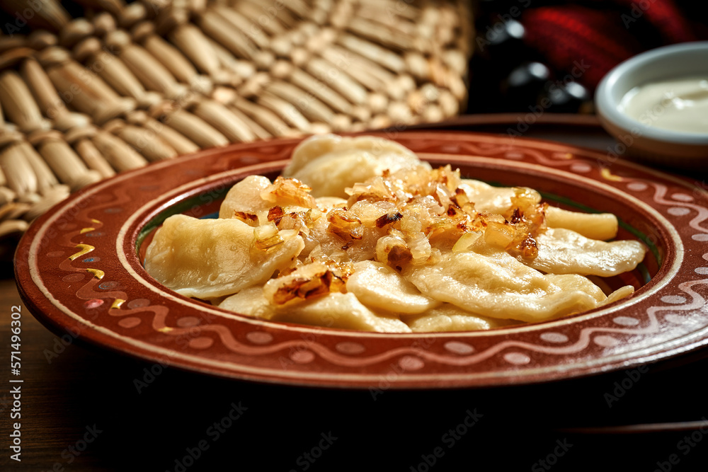 Traditional Ukrainian varenyky stuffed and fried onions in clay dishes. Ukrainian cuisine. Close up Traditional Ukrainian varenyky stuffed and fried onions in clay dishes. Ukrainian cuisine. Close up
