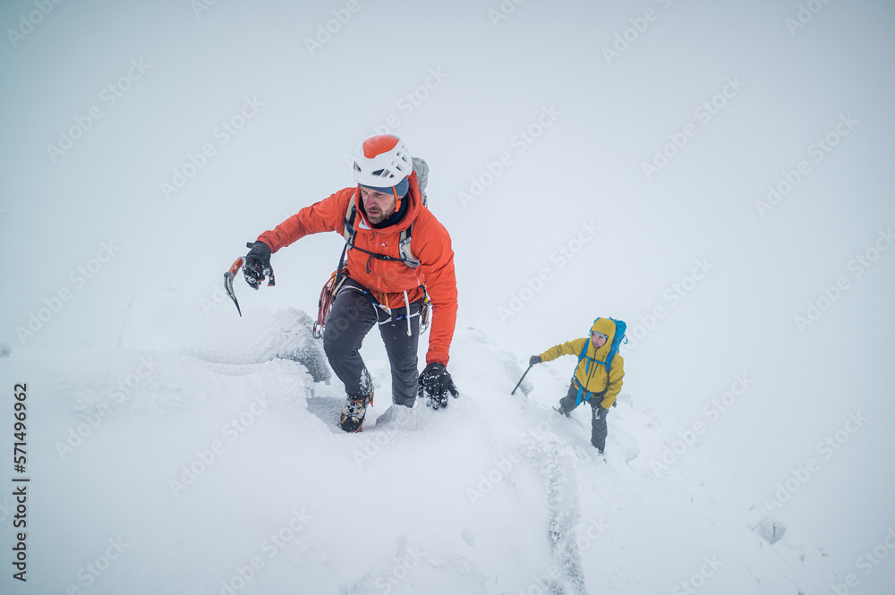 Ice climbers climbing a frozen alpine ridge on a mountain Ice climbers climbing a frozen alpine ridge on a mountain