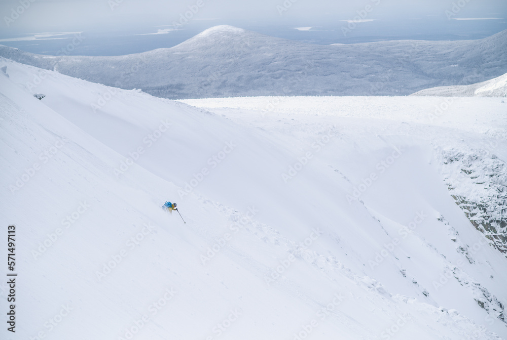Backcountry skier skiing snow field on wide open mountain Backcountry skier skiing snow field on wide open mountain