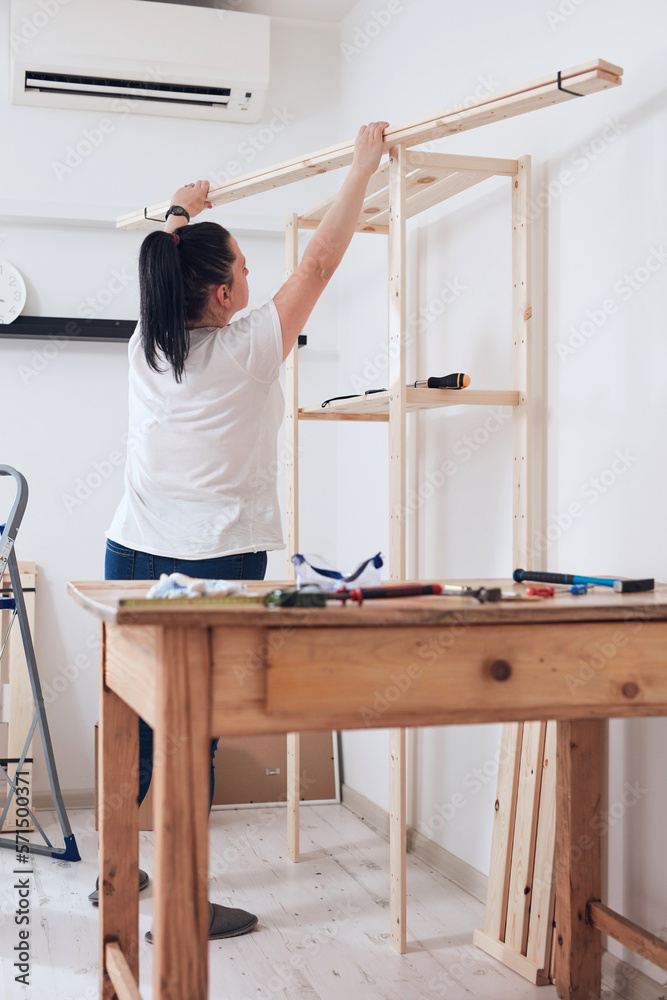 Woman assembling new wooden shelf and furniture in the apartment. Woman assembling new wooden shelf and furniture in the apartment.