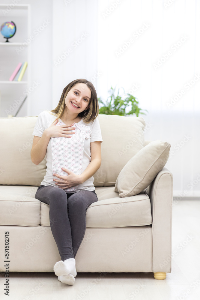 Photo of pregnant woman wearing casual clothes and holding childish clothes in hands. Photo of pregnant woman wearing casual clothes and holding childish clothes in hands.