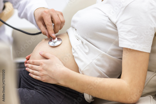 Cropped photo of doctor with stethoscope going to exam the pregnant woman.