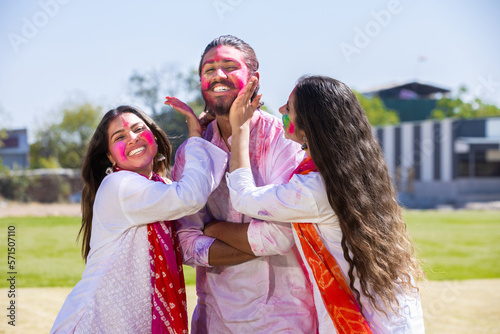 Happy young indian famiy play fholi with color powder or gulal outdoor at park.