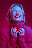 A happy woman is enjoying music while posing in studio isolated on magenta background. Viva magenta.