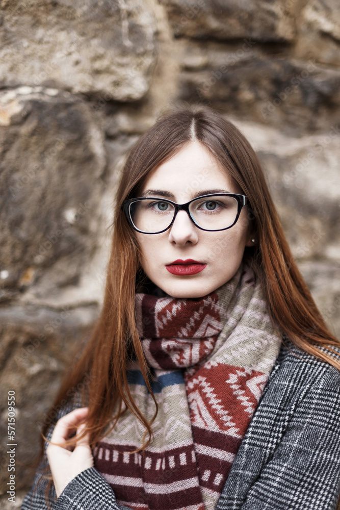 young woman in glasses wearing a coat wrapped in a scarf