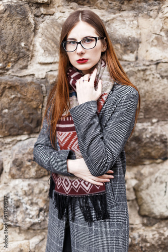 young woman in glasses wearing a coat wrapped in a scarf