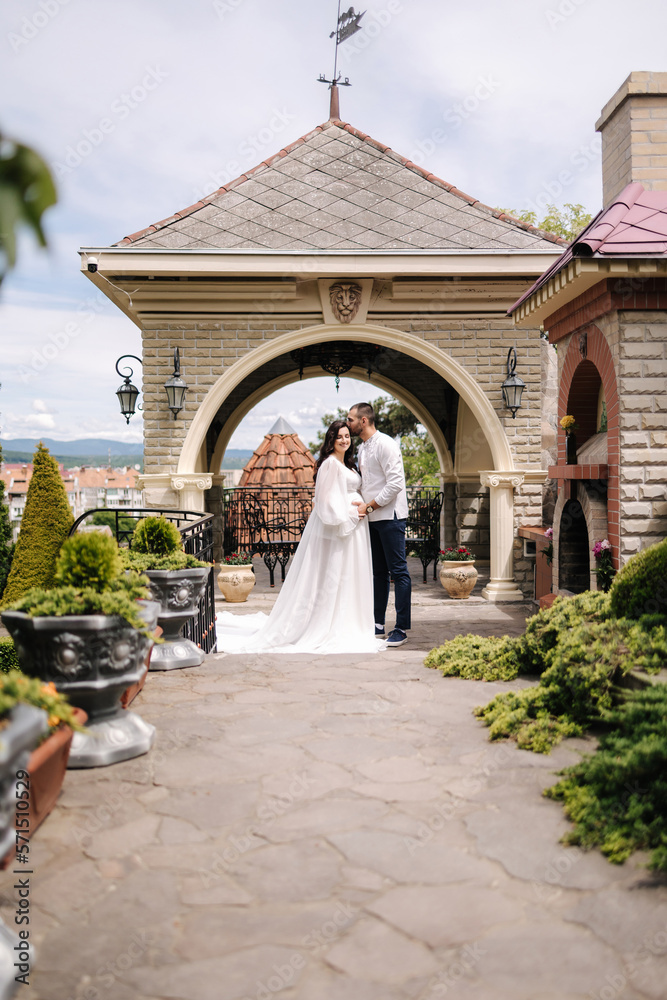 Obraz premium Elegant pregnant woman in luxury white dress walking aroung with her handsome husband