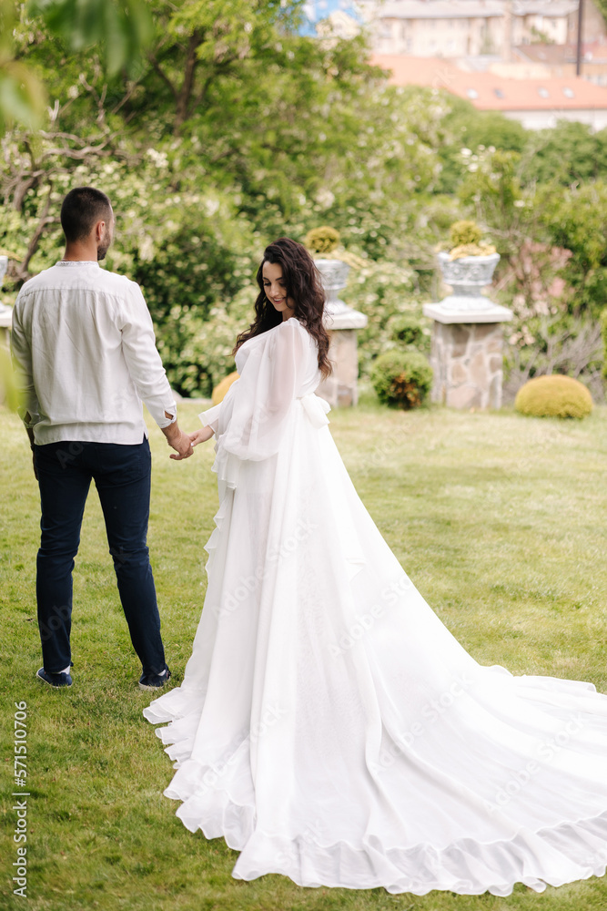 Elegant pregnant woman in luxury white dress walking aroung with her handsome husband