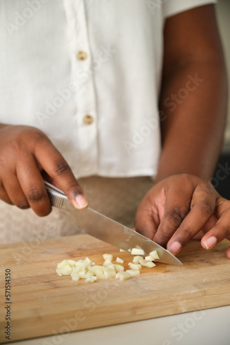 Close up of cuban woman hands cutting a raw garlic using a knife.