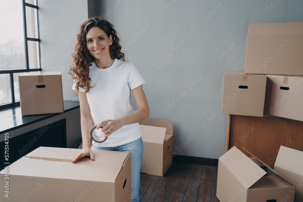 Mover is packing cargo with duct tape. Young lady is wrapping cardboard boxes with packing tape. Mover is packing cargo with duct tape. Young lady is wrapping cardboard boxes with packing tape.