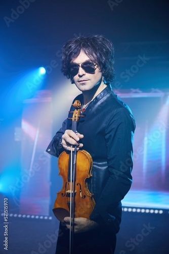 Violinist a player with a violin instrument in his hands. Artist of classical music or alternative music direction. Concept of stage art and performance.