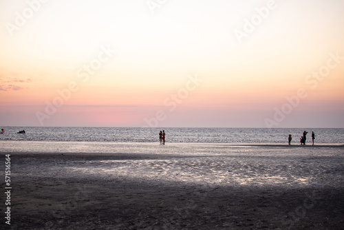 Grupo de personas fotografiándose en la playa al atardecer