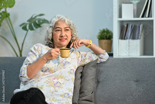 Satisfied middle aged lady drinking coffee, spending free time in morning at comfortable home