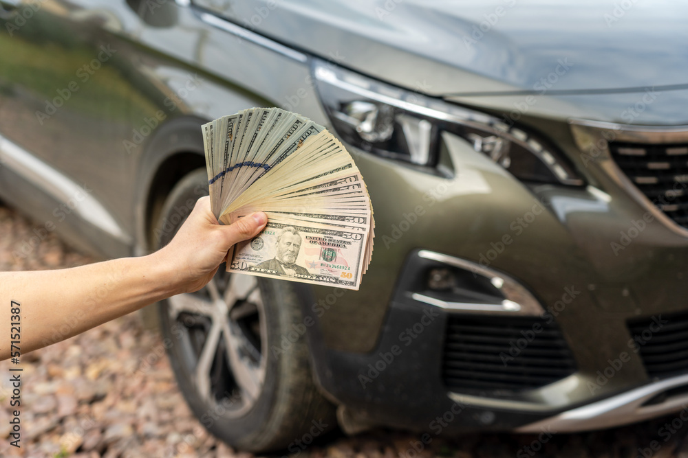 Person with money in the hands standing front car. Insurance, loan concept. Deal of buy or rent new car Person with money in the hands standing front car. Insurance, loan concept. Deal of buy or rent new car