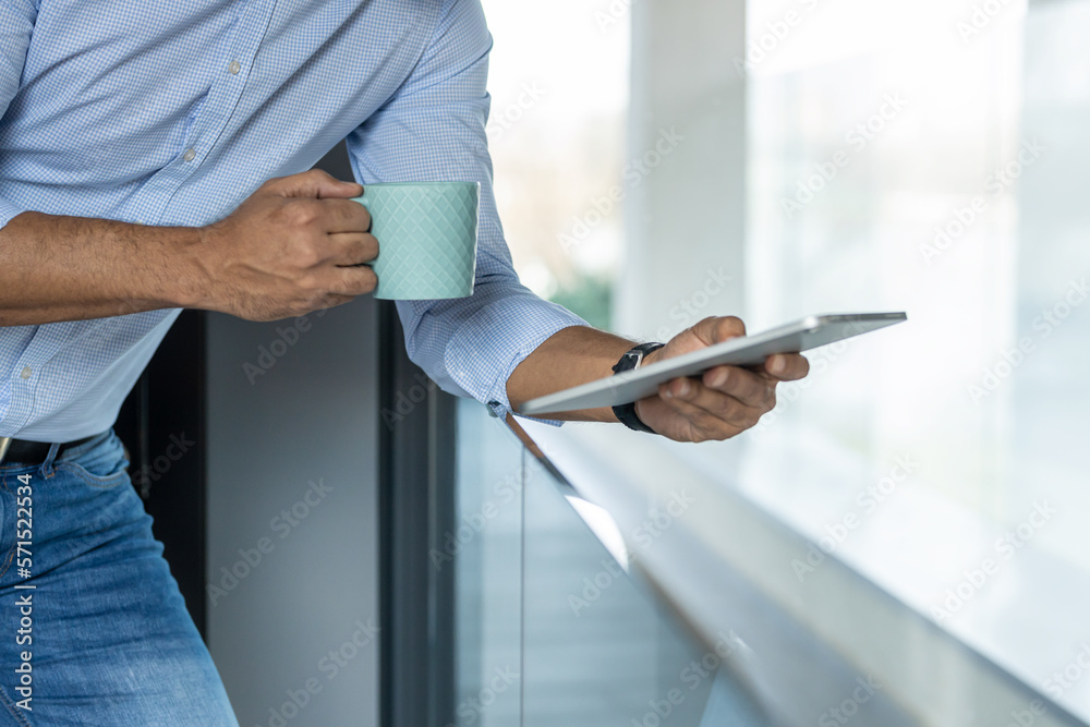 Close up of a man holding a coffee mug and a tablet Close up of a man holding a coffee mug and a tablet