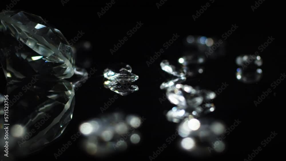 Slow turning large cristal clear diamond with smaller shiny diamonds on a dark mirroring surface to indicate luxury or wealth or as a gift for special occations like weddings or valentines day. Slow turning large cristal clear diamond with smaller shiny diamonds on a dark mirroring surface to indicate luxury or wealth or as a gift for special occations like weddings or valentines day.