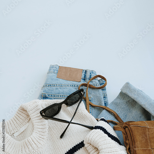Aesthetic casual fashion composition with female clothes and accessories. Striped sweater, suede bag, jeans, sunglasses. Flat lay, top view.