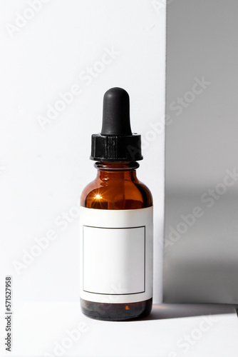 Amber glass dropper with black pipette and white moke up label on white background with shadow. Aestethic image for abstract cosmetic product, serum, oil y etc
