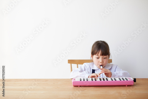 テーブルで鍵盤ハーモニカをする女の子 photo