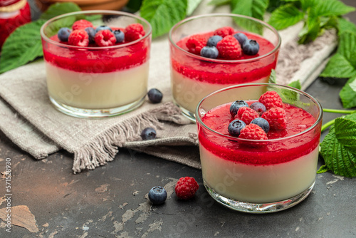 Delicious italian dessert panna cotta with berry sauce on a dark background in small jars. place for text photo