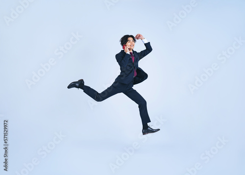 Wallpaper Mural スマホで通話しながらジャンプする若いビジネスマン Torontodigital.ca