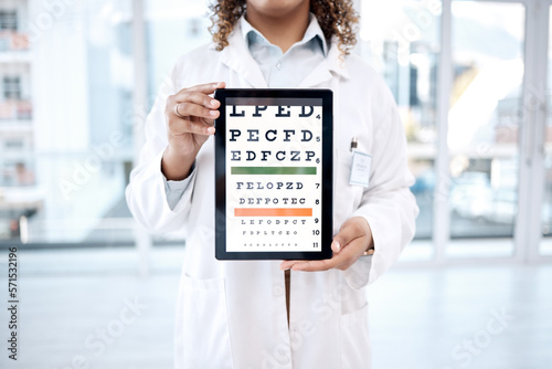 Hands, optometry chart and tablet screen in hospital for vision examination in clinic. Healthcare, snellen or woman, ophthalmologist or medical doctor holding technology showing letters for eye test. photo