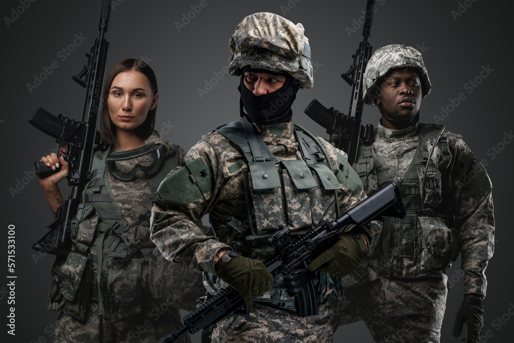 Multiethnic military team of three soldiers with rifles against grey background. Multiethnic military team of three soldiers with rifles against grey background.