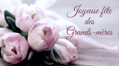 carte ou bandeau pour souhaiter une joyeuse fête des grands-mères en mauve sur un fond gris et blanc en effet bokeh et à côté un bouquet de fleurs mauve des tulipes photo