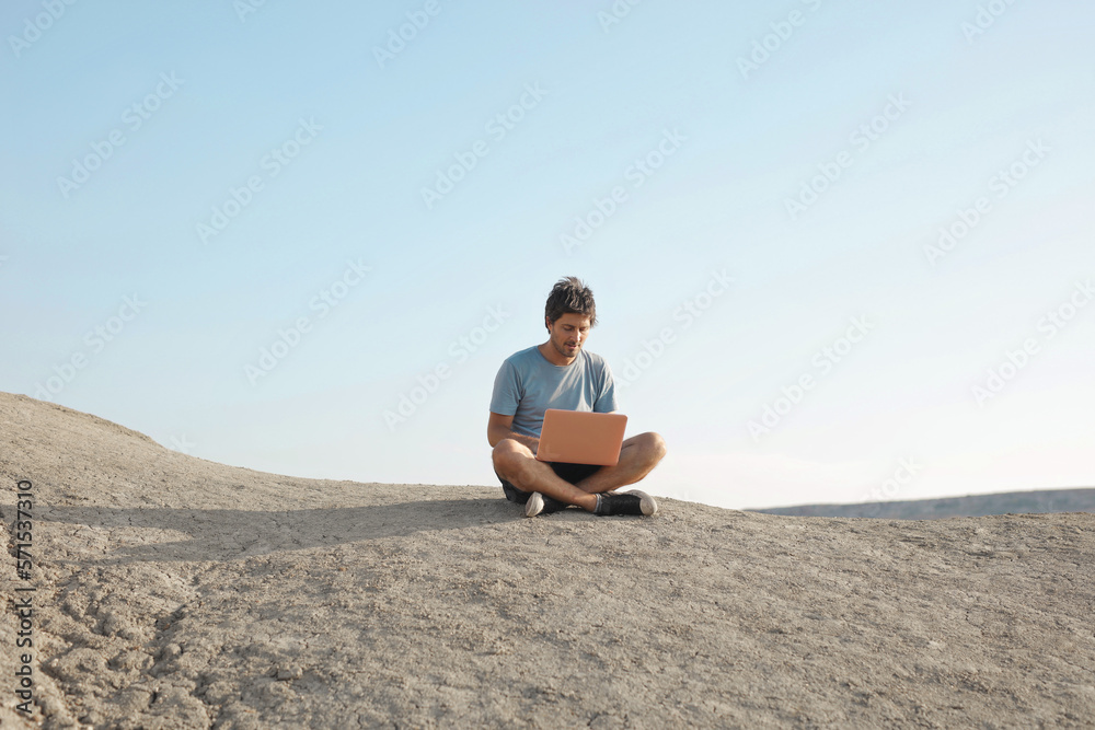 lonely man in the desert uses a computer